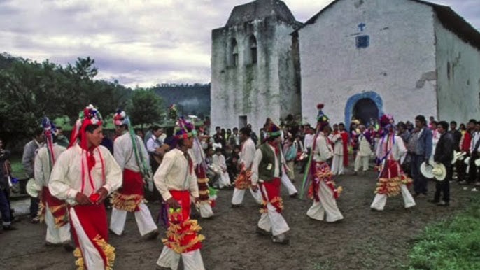 Integrantes de la comunidad Ódami del norte realizando una danza ceremonial frente a una iglesia durante una festividad tradicional.