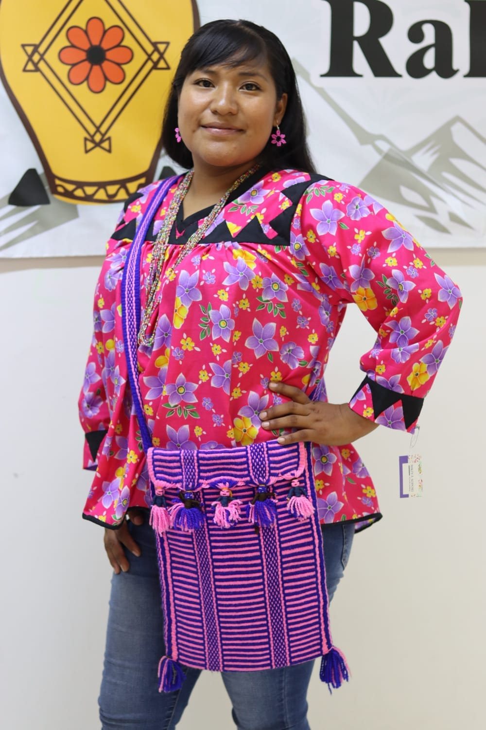 Mujer con blusa floral rosa y accesorios textiles tejidos en tonos morados.