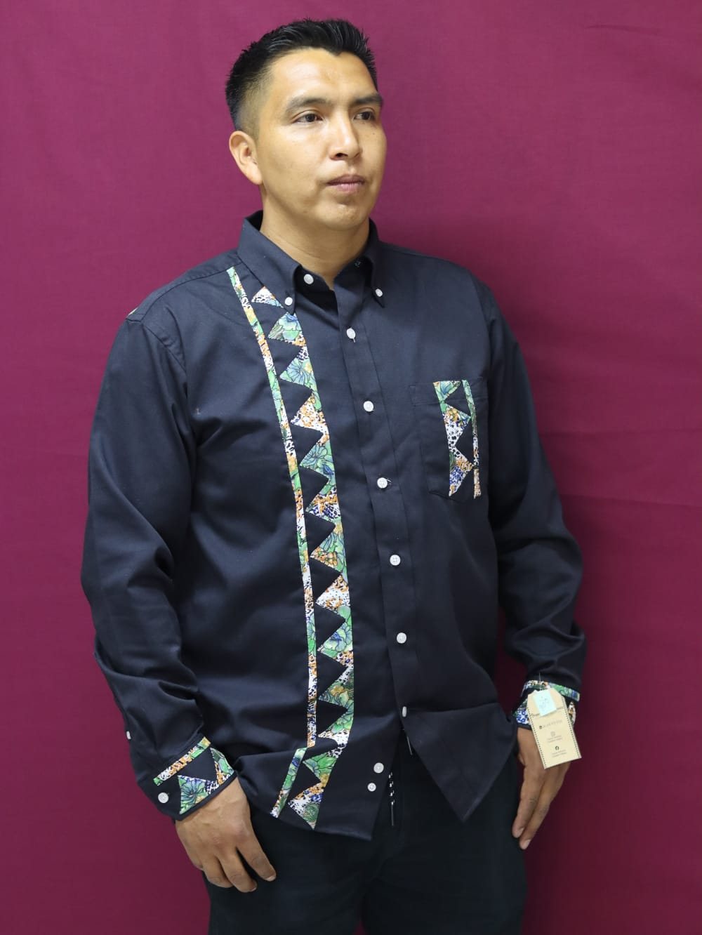 Hombre modelando una camisa negra con franjas textiles geométricas en el frente y los puños.