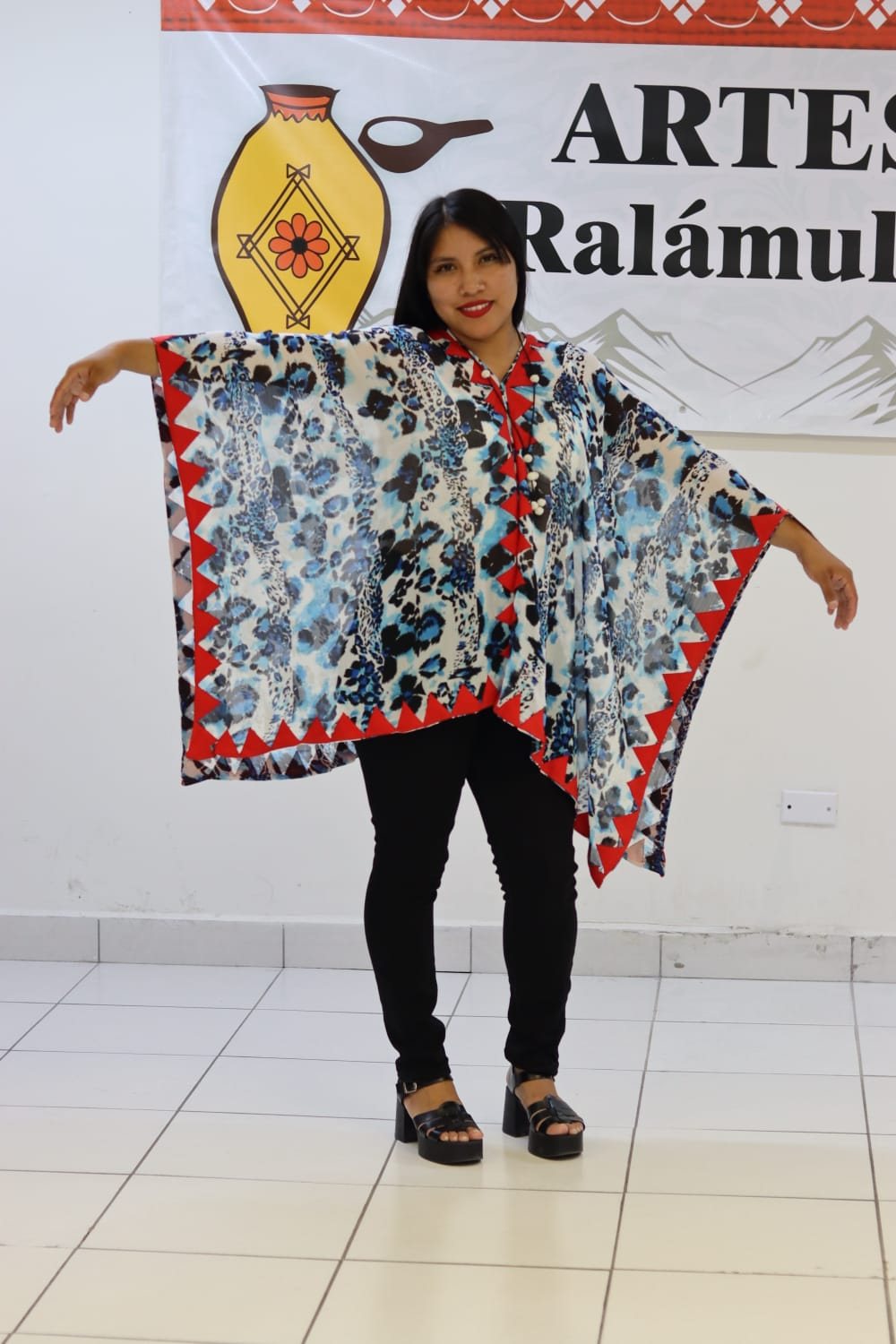Mujer mostrando una prenda amplia de estampado floral con borde geométrico rojo y negro.
