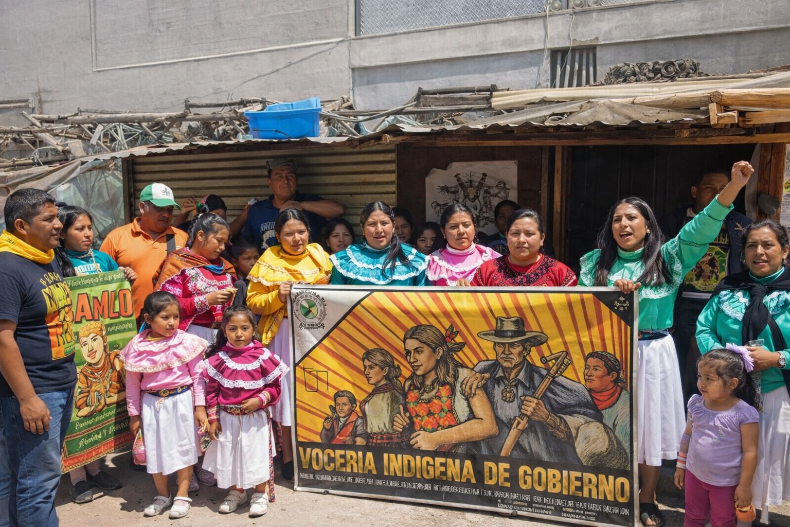 Mujeres, hombres y niñas de la comunidad Ódami del norte reunidos en un acto comunitario con vestimenta tradicional y una manta de representación indígena.