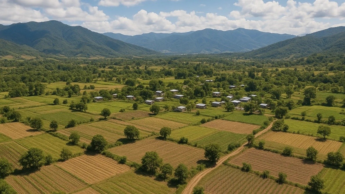 Vista aérea de una comunidad Ódami del norte rodeada de campos de cultivo, caminos rurales y montañas de la Sierra Madre bajo un cielo despejado.